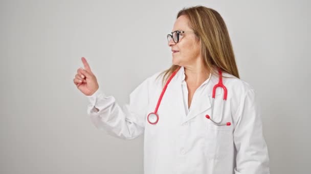 中年のヒスパニック系女性医師 孤立した白い背景の上に側を指す笑顔 — ストック動画