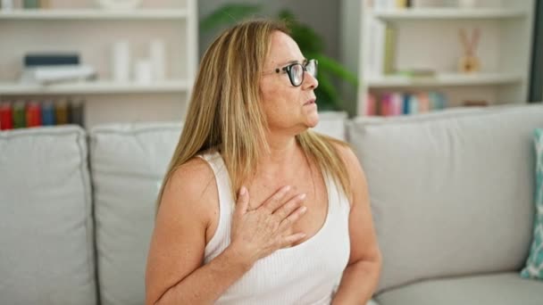 中年人惊慌失措的女人坐在沙发上 在家里心脏病发作 — 图库视频影像