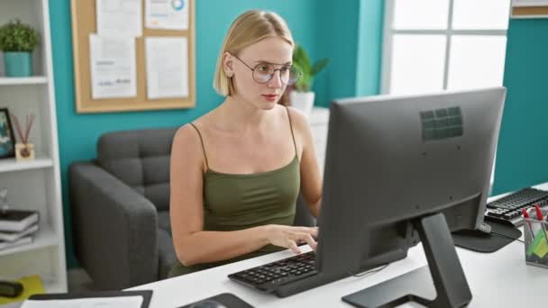 若い金髪女性ビジネスワーカー オフィスでコンピュータの読書文書を使用して — ストック動画