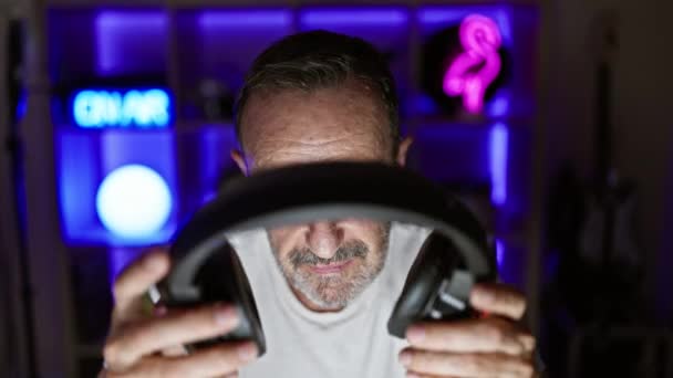 严肃的中年男人 灰白的头发 沉浸在家中的游戏室里 一边戴着耳机 一边主宰着虚拟世界 — 图库视频影像
