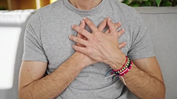 Young Hispanic Man Sitting Sofa Hands Heart Home — Stok video