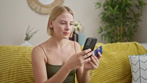 Ung Blond Kvinna Shopping Med Smartphone Och Kreditkort Förvånad Hemma — Stockvideo