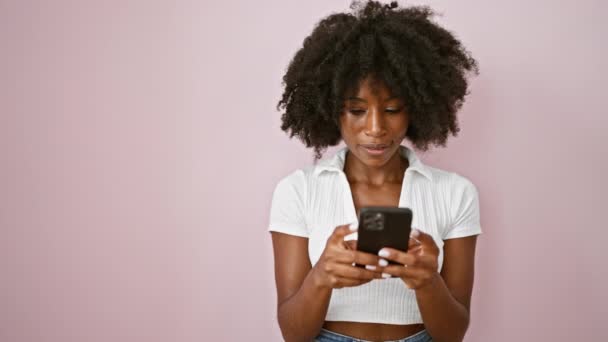 孤立したピンクの背景の上側を見ているスマートフォンを使用してアフリカ系アメリカ人女性 — ストック動画