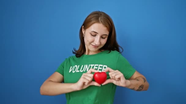 Молодая Женщина Волонтер Держит Сердце Над Грудью Изолированном Синем Фоне — стоковое видео