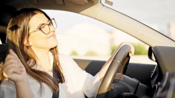 若い美しいヒスパニック系の女性が道路上で眼鏡をかけて笑って車を運転 — ストック動画