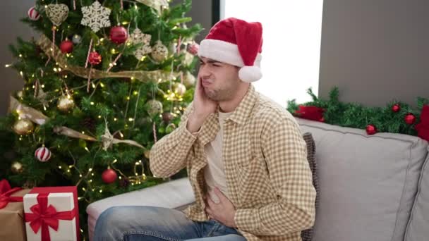 Young Hispanic Man Suffering Stomach Ache Sitting Christmas Tree Home — Stock Video