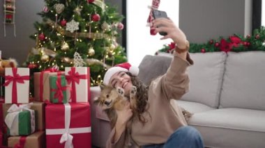 Köpekli genç İspanyol kadın, akıllı telefonla Noel 'i evde kutlayarak selfie çekiyor.
