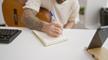 Yakışıklı genç adam, rahat ve konsantre, klasik müzik besteleyen, rahat müzik stüdyosunda akustik gitar çalan