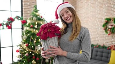Kafkasyalı genç bir kadın elinde Noel bitkisi tutuyor.