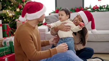 Çift ve oğul Noel ağacının yanında oturmuş evde oynuyorlar.