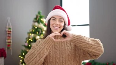 Genç, güzel, İspanyol bir kadın Noel 'i kutluyor. Elleri sokakta kalp şeklinde.