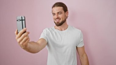 İzole edilmiş pembe arka planda kendine güvenen genç İspanyol bir adam.