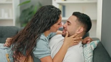 Erkek ve kadın çift birbirlerine sarılıyorlar koltukta oturmuş evde öpüşüyorlar.