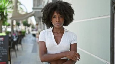 African american woman standing with serious expression and arms crossed gesture at street