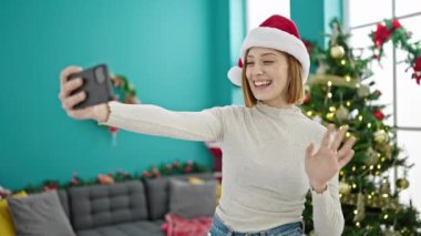 Sarışın genç bir kadın, evde Noel 'i kutlamak için el sallıyor.