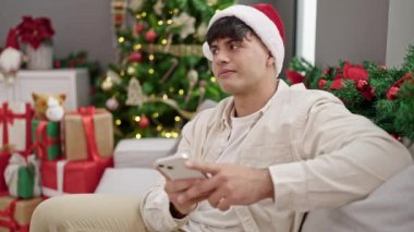 Genç İspanyol adam akıllı telefon kullanarak Noel 'i evde kutluyor.