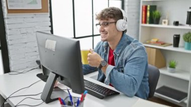 Ofiste çalışan genç İspanyol bir adam, güçlü bir kahvaltıda bir profesyonelin portresi kahve içiyor, bilgisayar kullanıyor, kulaklık takıyor ve internetten video görüşmeleri yapıyor.