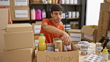 Gönüllü olan genç, yakışıklı, İspanyol asıllı adamın yürek ısıtan bir fotoğrafı. Yardım merkezindeki telefonda konuşmaya dalmış, bağışlarla topluma yardım ediyor.