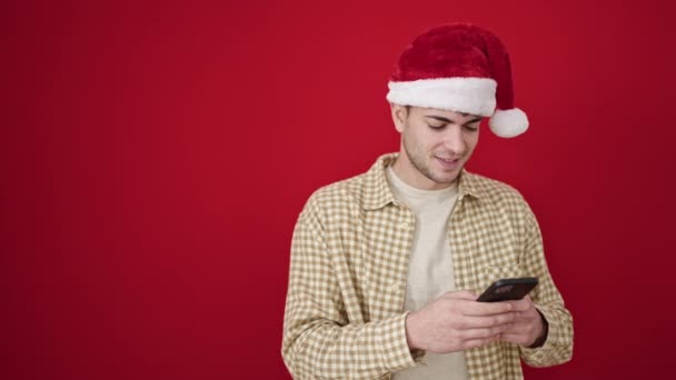 Junger Hispanischer Mann Trägt Weihnachtsmütze Mit Smartphone Und Blickt Zur — Stockvideo