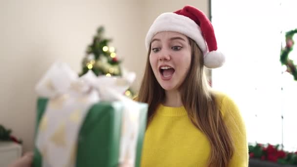 年轻的金发女人拿着礼物站在家里的圣诞树旁 — 图库视频影像