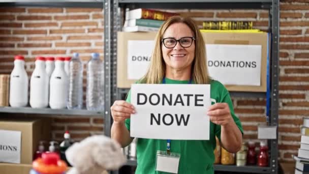 Medelålders Latinamerikanska Kvinna Volontär Håller Donera Meddelande Papper Välgörenhetscenter — Stockvideo