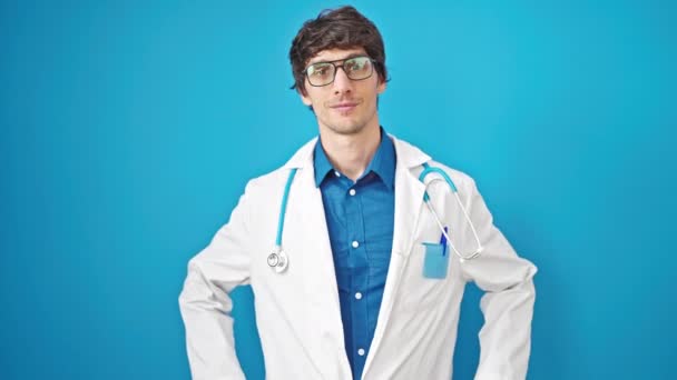 Jeune Homme Hispanique Médecin Souriant Confiant Debout Sur Fond Bleu — Video