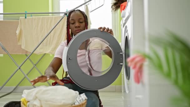 一个心平气和的非洲裔美国女人迷人的肖像 她勤勤恳恳地做家务活 坐在地板上 同时在自家洗衣房洗衣服 — 图库视频影像