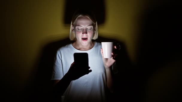 Ung Blondine Kvinde Ved Hjælp Smartphone Drikker Kaffe Gabende Isoleret – Stock-video