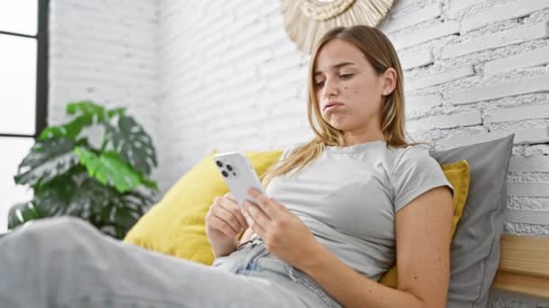 Młoda Atrakcyjna Blondynka Siedząca Wygodnie Łóżku Zanurzona Korzystaniu Smartfona Relaksujący — Wideo stockowe