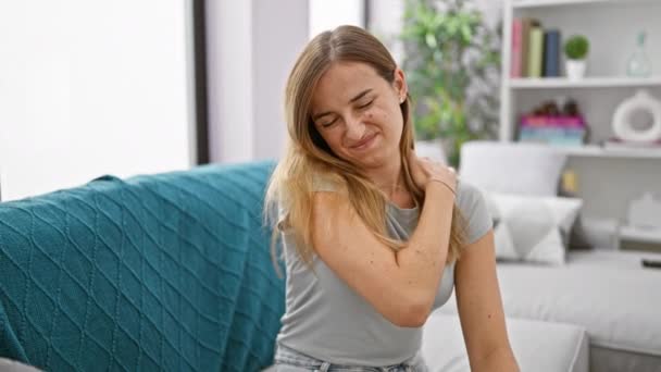 精疲力竭的金发女子坐在沙发上 在家里得了严重的颈痛 — 图库视频影像