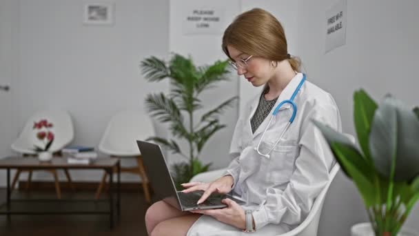 Młoda Blondynka Lekarz Pomocą Laptopa Siedzi Krześle Klinice Poczekalnia — Wideo stockowe