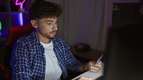 ゲームルームでコンピュータとクレジットカードを使用して若いアラブ男ストリーマー — ストック動画