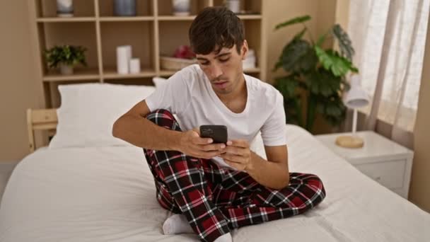 Verontruste Jonge Spaanse Man Zit Zijn Comfortabele Bed Serieus Kijken — Stockvideo