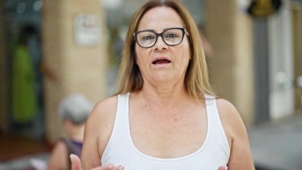 Middelbare Leeftijd Spaanse Vrouw Staat Met Ernstige Uitdrukking Spreken Straat — Stockvideo