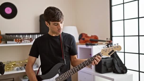 Zelfverzekerde Lachende Jonge Spaanse Man Beheerst Elektrische Gitaar Muziekstudio Portretteert — Stockvideo