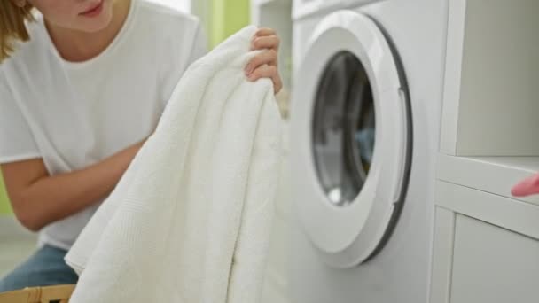 洗濯室できれいなタオルと洗剤ボトルを持っている若い金髪の女性 — ストック動画