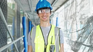 Genç İspanyol mimar inşaat alanında kendine güvenerek gülümsüyor.