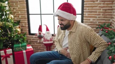 Evde Noel şapkası takan, midesi ağrıyan genç bir İspanyol.