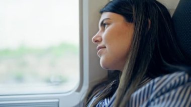 Genç, güzel İspanyol kadın mutlu bir şekilde gülümsüyor. Tren vagonunun içinden bakıyor.