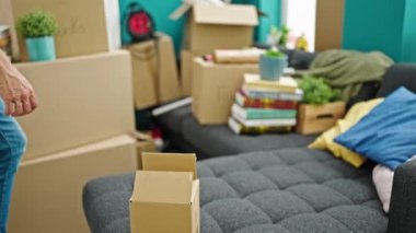 Genç İspanyol adam yeni evinde yorgun bir şekilde kanepede oturuyor.