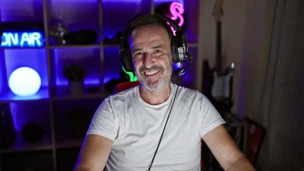 Uśmiechnięty Mężczyzna Średnim Wieku Siwymi Włosami Rządzący Strumieniem Słuchawki Założone — Wideo stockowe
