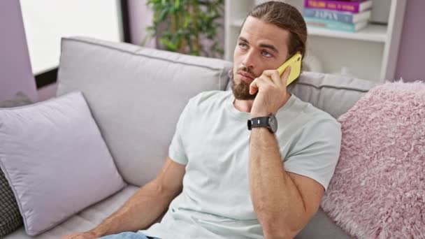 Jovem Hispânico Falando Telefone Sentado Sofá Bocejando Casa — Vídeo de Stock