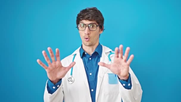 Молодий Іспаномовний Лікар Робить Спокійний Жест Над Ізольованим Синім Тлом — стокове відео