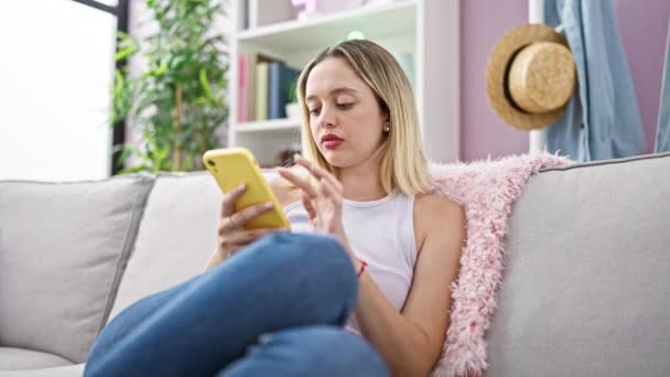 Jeune Femme Blonde Utilisant Smartphone Assis Sur Canapé Pensant Maison — Video