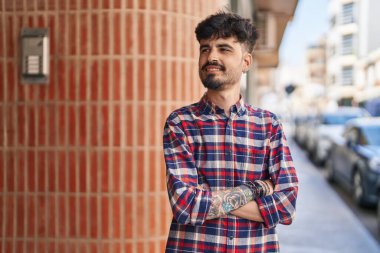 Genç İspanyol adam gülümsüyor. Kendine güveni tam. Sokakta çapraz hareketlerle duruyor.