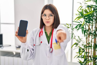 Genç İspanyol doktor kamerayı işaret ederek akıllı telefon ekranı gösteriyor ve sen kendine güvenen ciddi bir hareket yapıyorsun. 