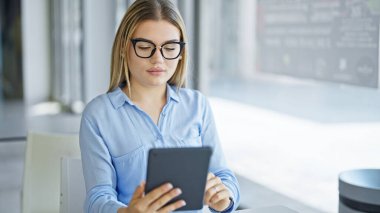 Ofiste dokunmatik ped kullanan genç sarışın bir iş kadını.