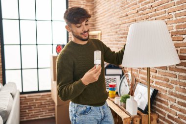 Young arab man smiling confident changing lightbulb at new home