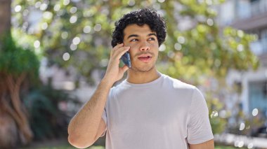 Parktaki akıllı telefondan konuşan genç latin adam.