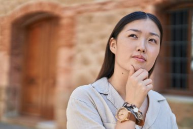 Chinese woman standing with doubt expression at street